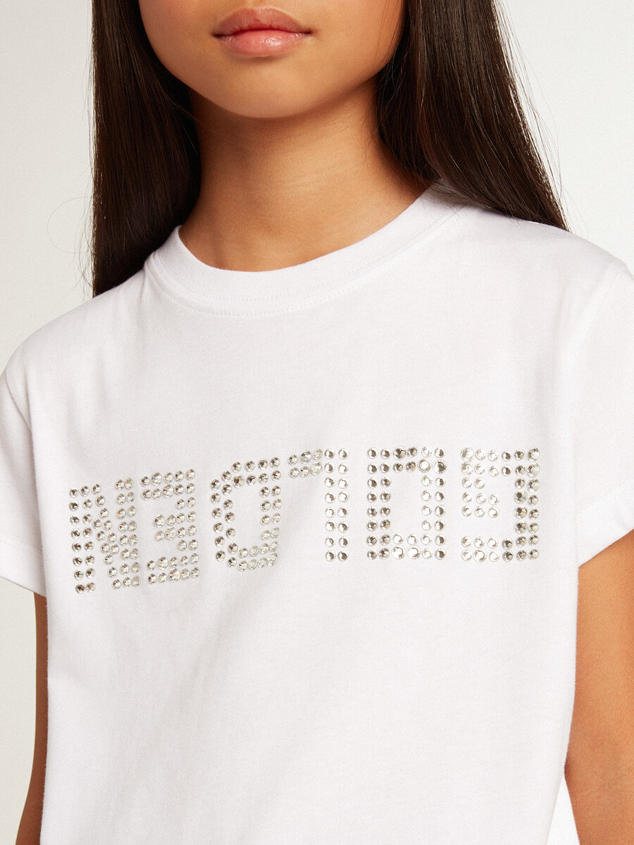 camiseta branca com letras douradas em cristais ao centro.