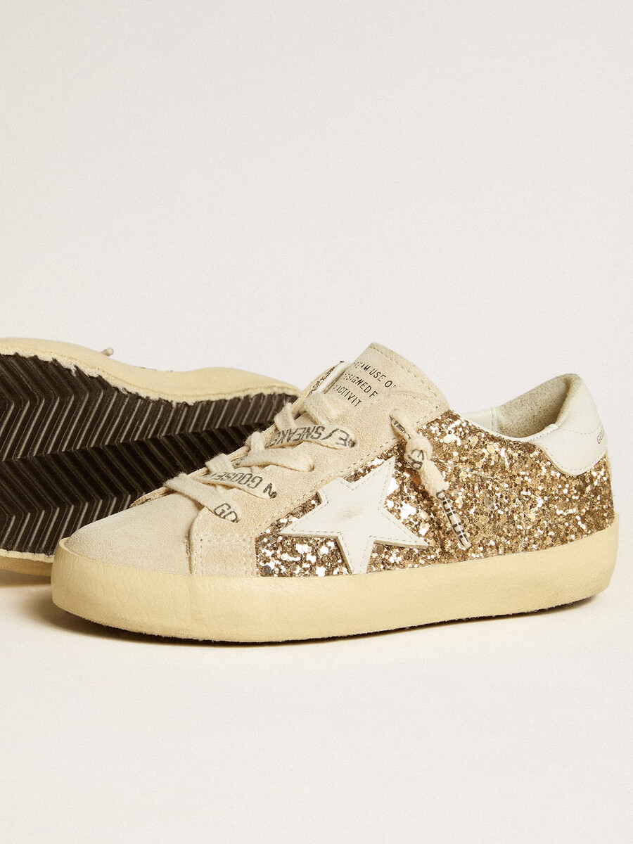 super-star junior em glitter dourado com estrela de couro branco e detalhe no calcanhar.