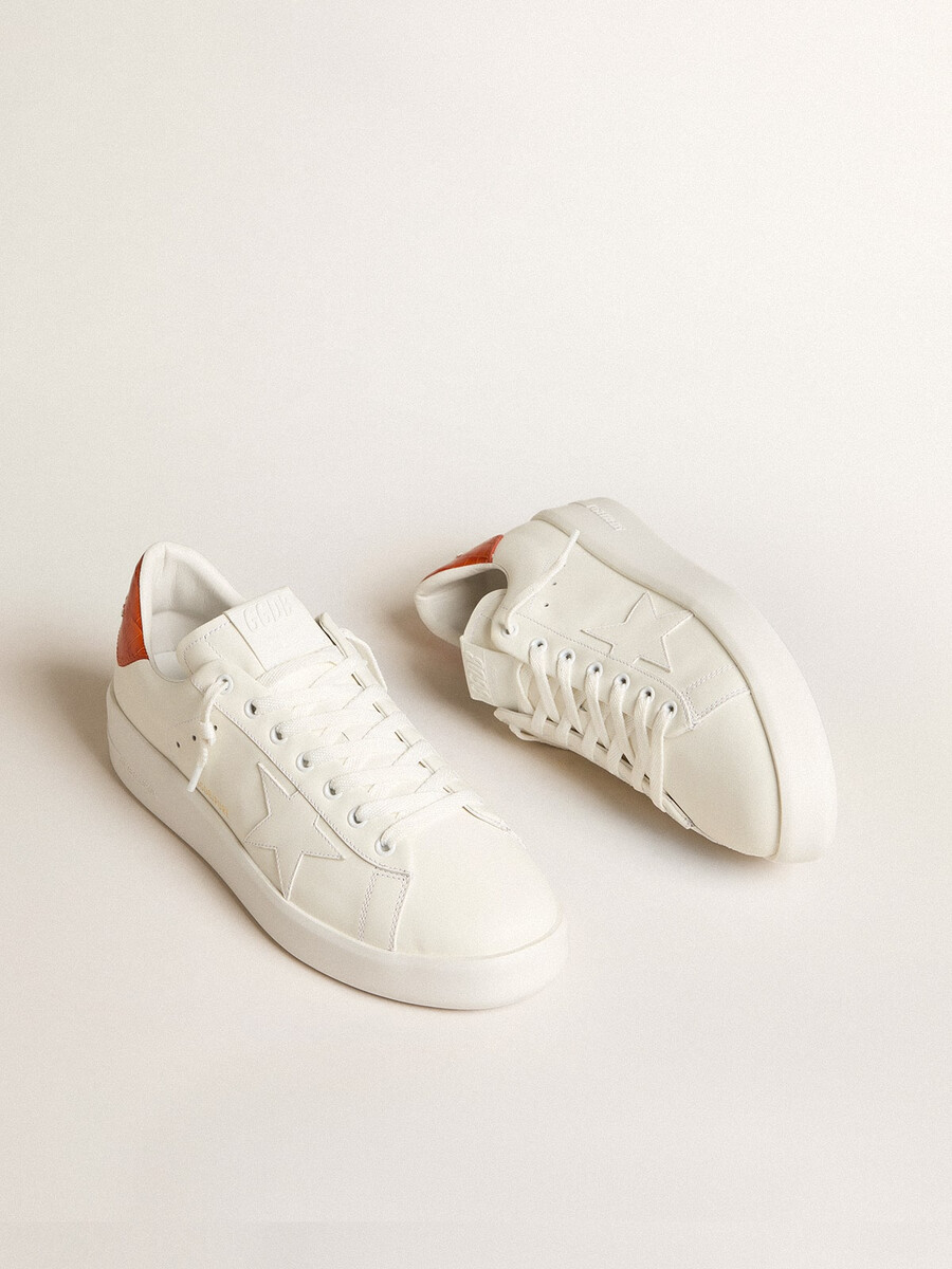 tênis masculino purestar com estrela de couro branca e detalhe laranja no calcanhar.