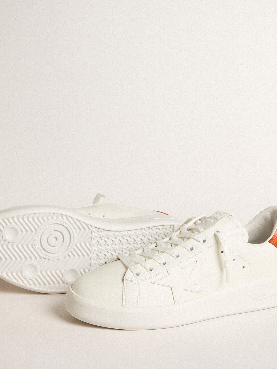 tênis masculino purestar com estrela de couro branca e detalhe laranja no calcanhar.