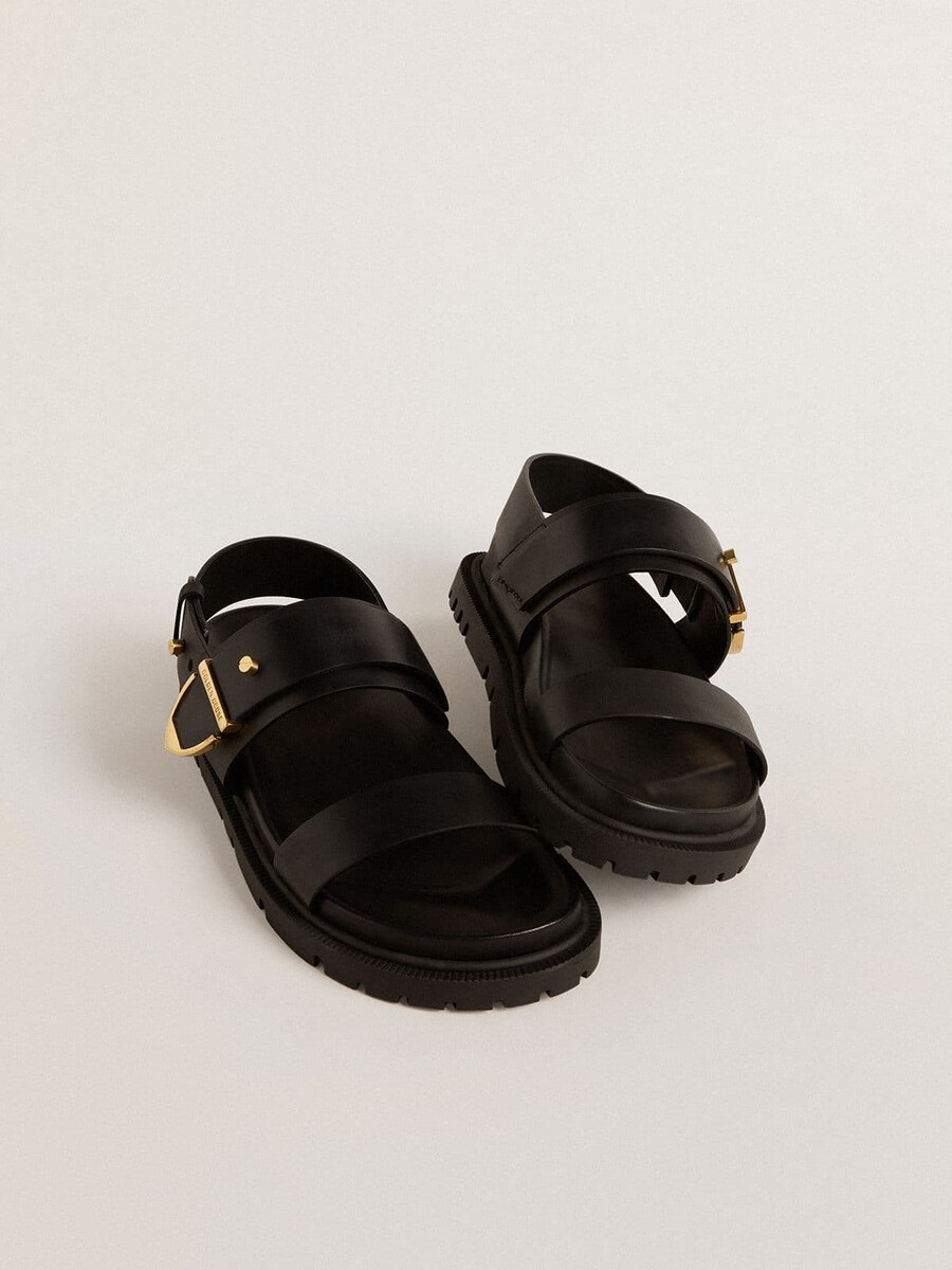 sandália feminina lucy em couro preto brilhante com fivela de metal dourado.