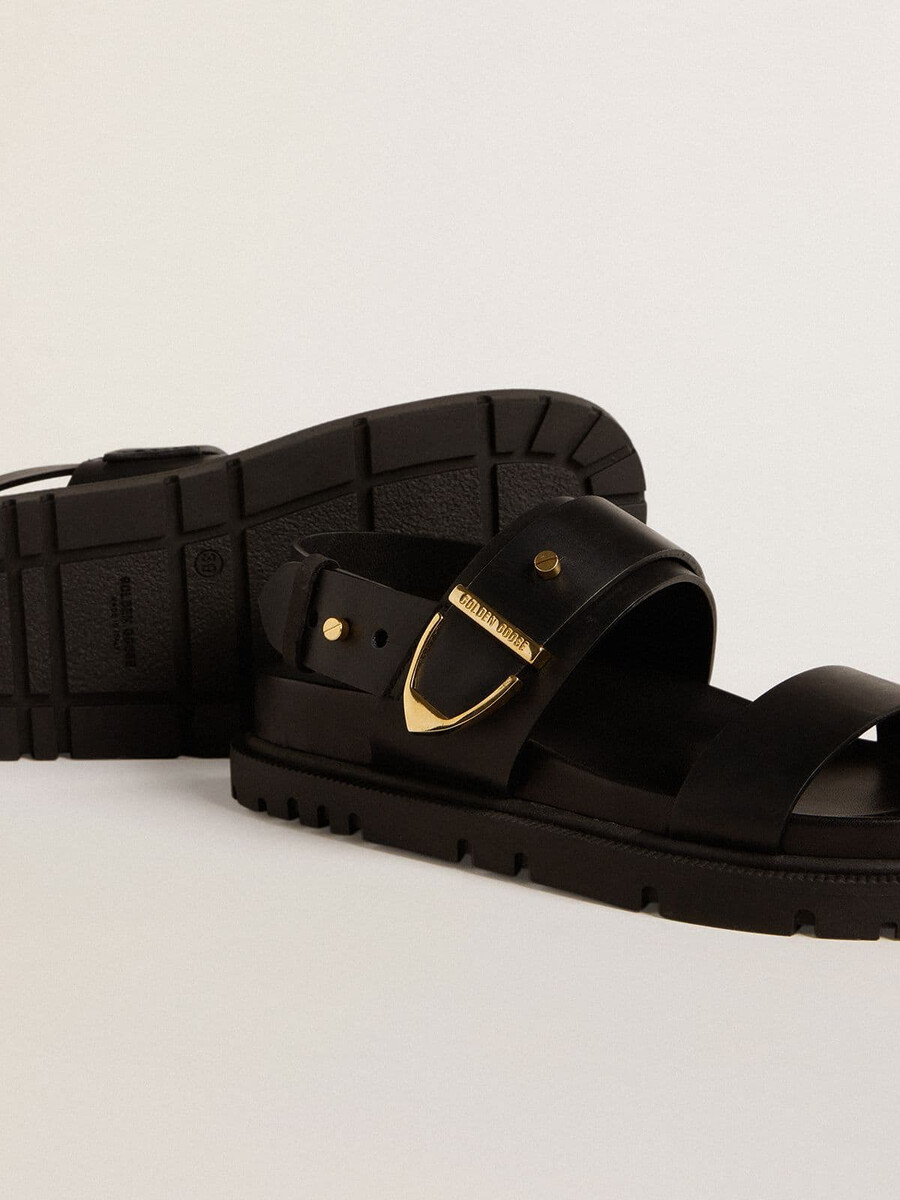 sandália feminina lucy em couro preto brilhante com fivela de metal dourado.