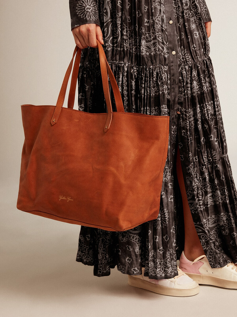 bolsa pasadena em couro martelado brilhante na cor bege com logotipo dourado na parte frontal.