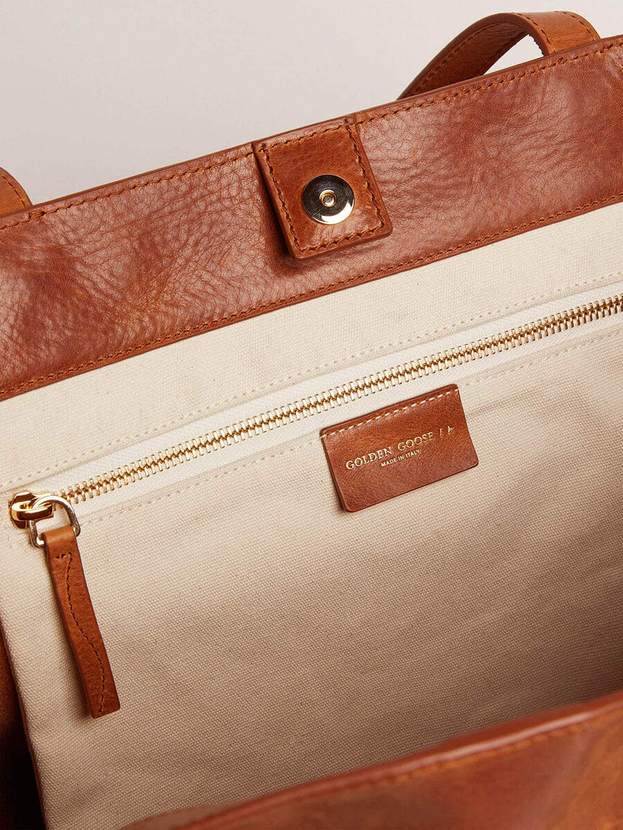 bolsa pasadena em couro martelado brilhante na cor bege com logotipo dourado na parte frontal.