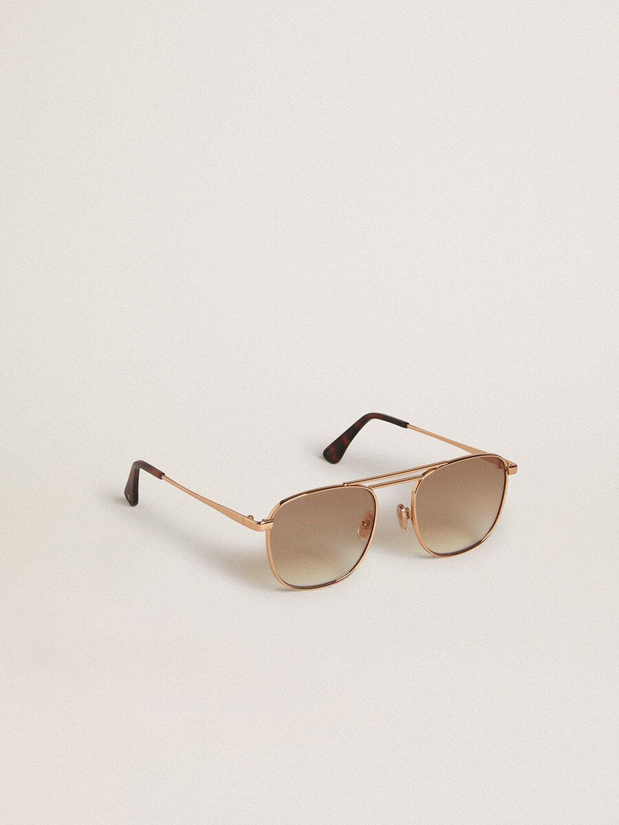 Óculos de sol estilo aviador com armação dourada e lentes bege.