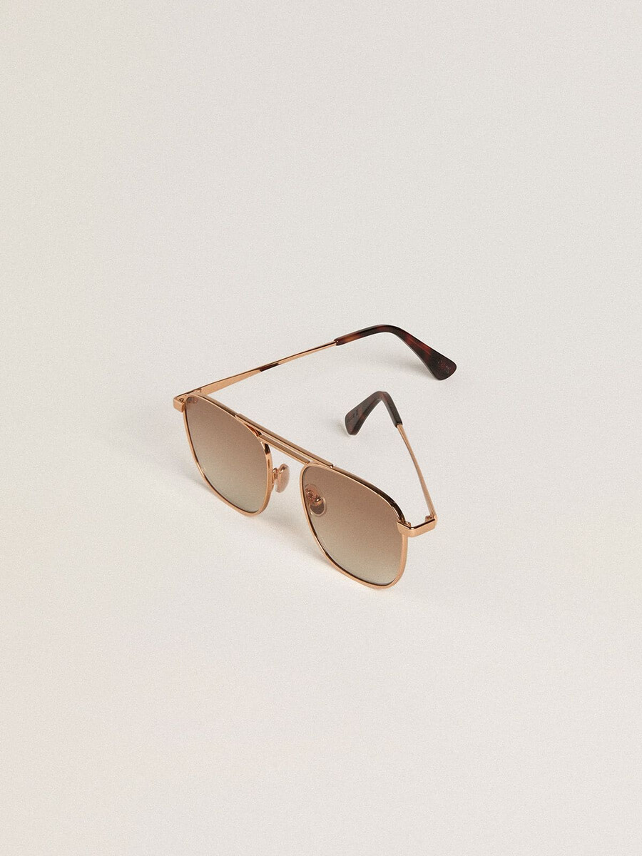 Óculos de sol estilo aviador com armação dourada e lentes bege.