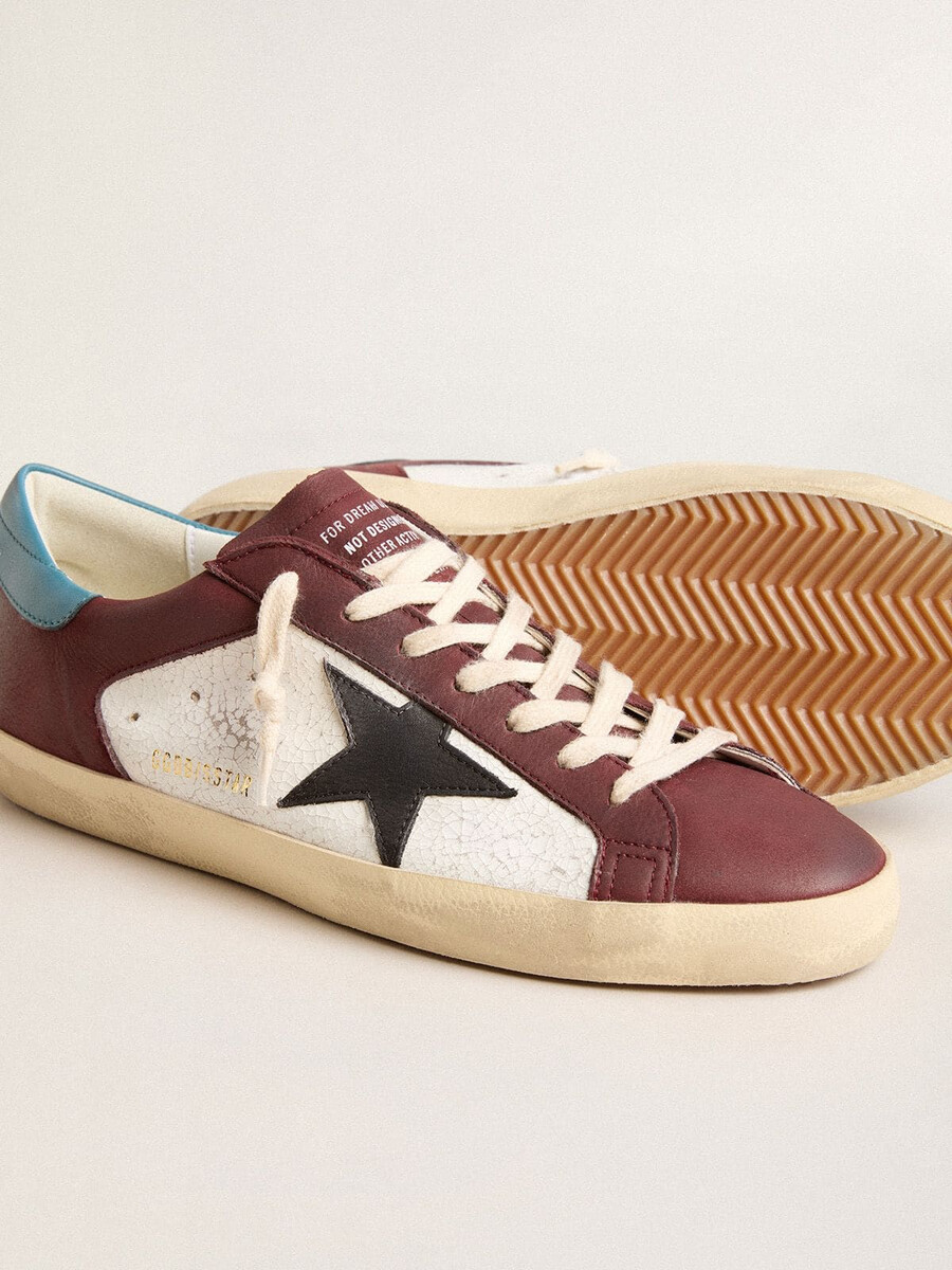 tênis masculino super-star em couro craquelado com estrela marrom e detalhe azul-petróleo no calcanhar.