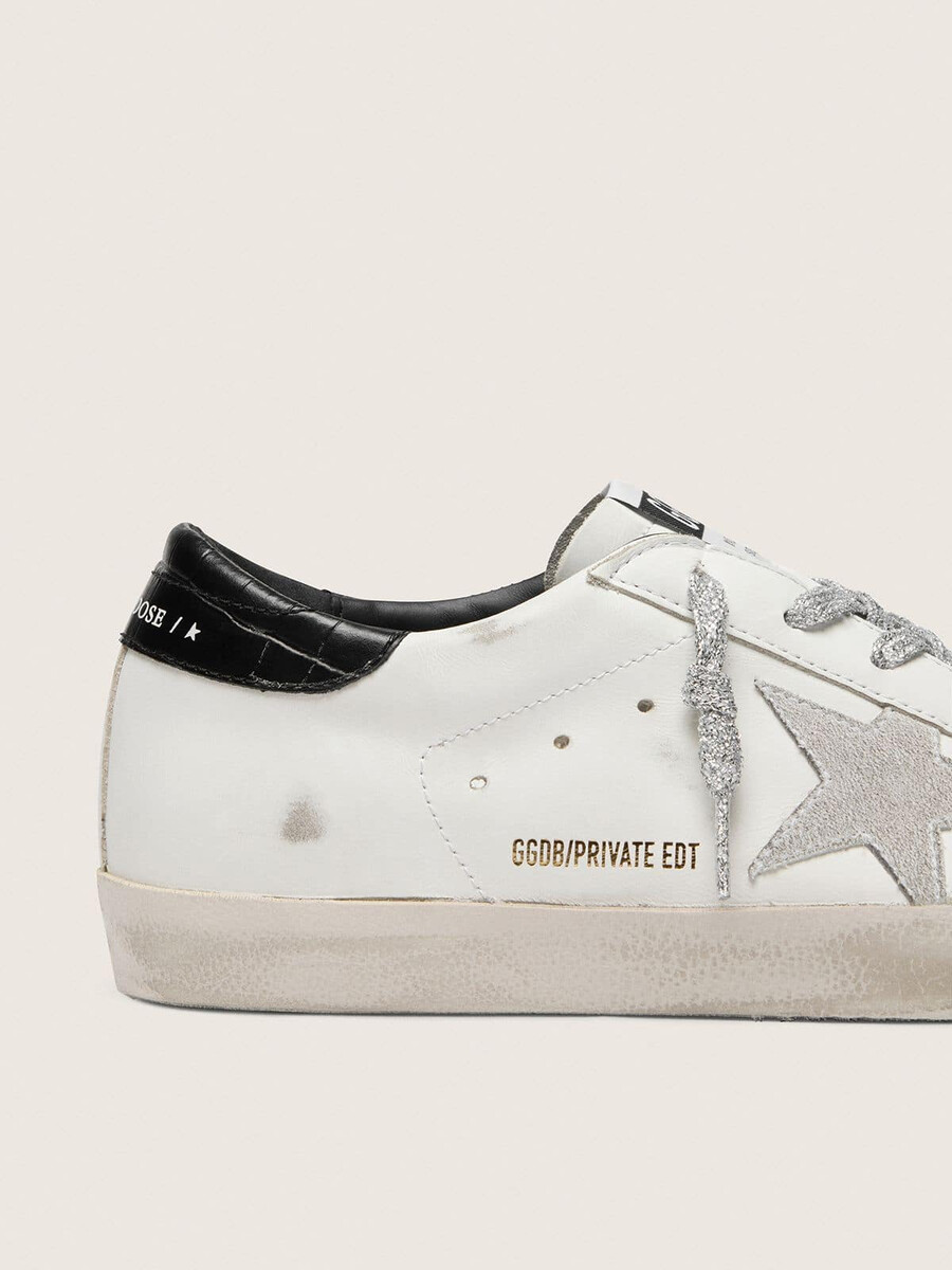 sapato feminino super-star com estrela em camurça branca e detalhe em couro preto com estampa de crocodilo no calcanhar.