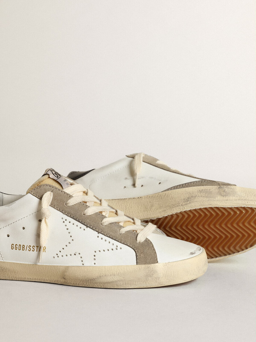tênis super-star feminino com estrela perfurada e detalhe azul-marinho no calcanhar.