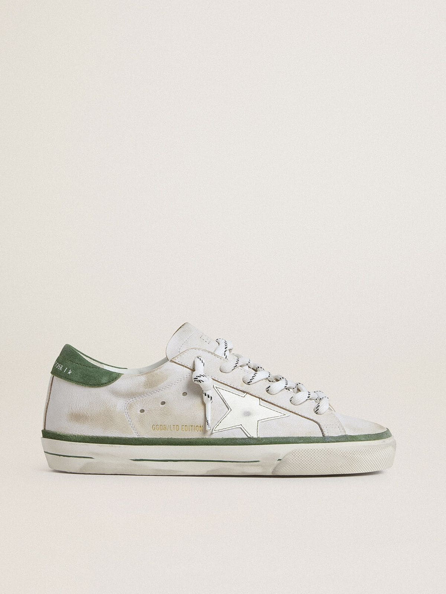 tênis feminino super-star ltd com estrela de couro branco e detalhe de camurça verde no calcanhar.