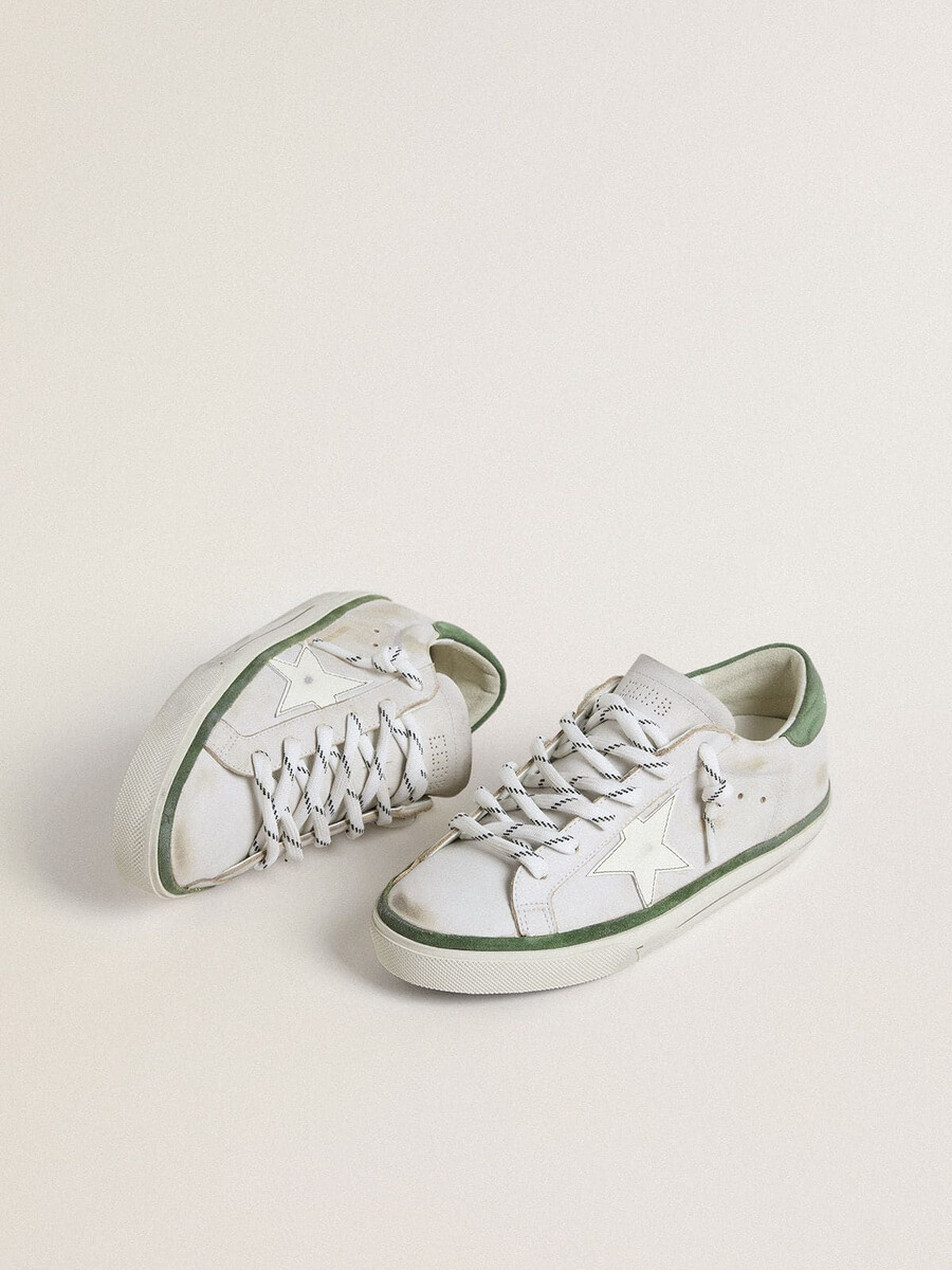 tênis feminino super-star ltd com estrela de couro branco e detalhe de camurça verde no calcanhar.