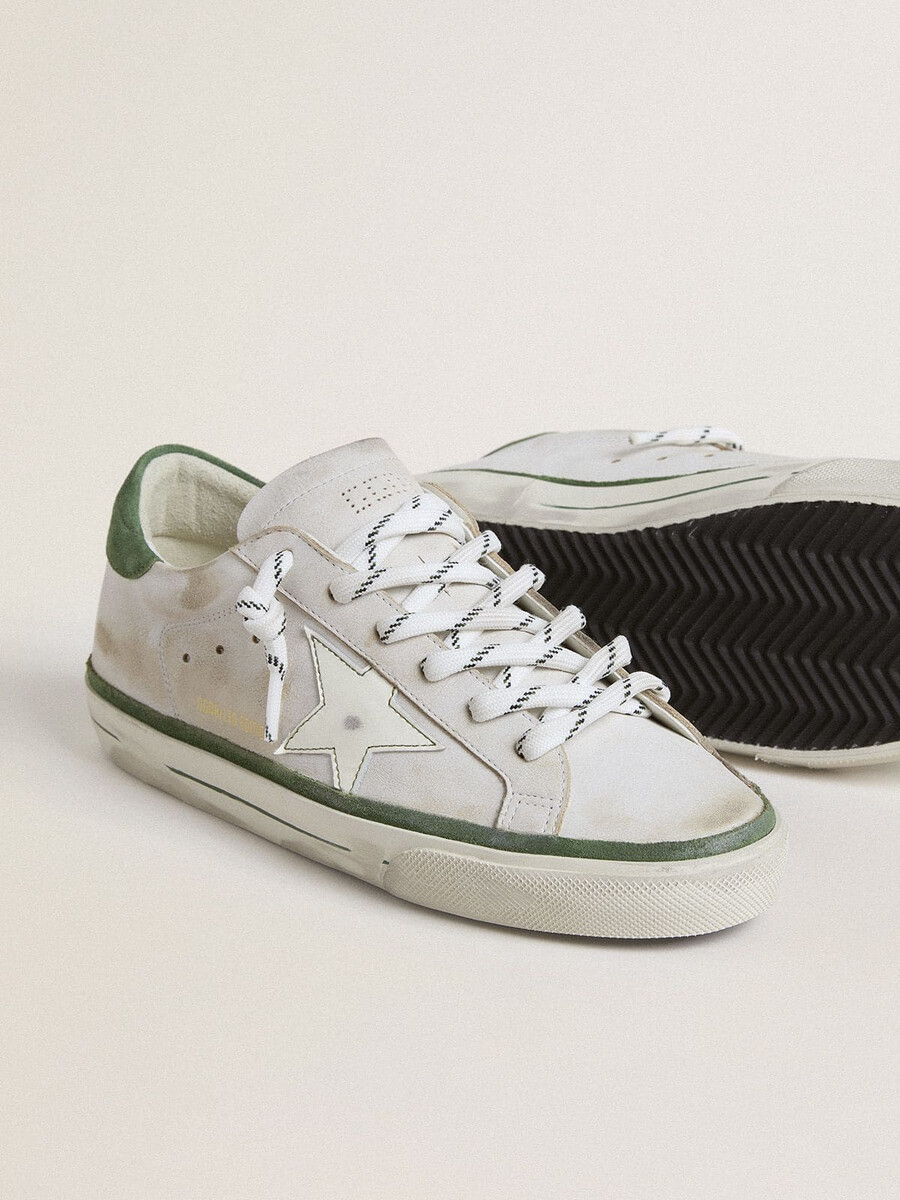 tênis feminino super-star ltd com estrela de couro branco e detalhe de camurça verde no calcanhar.