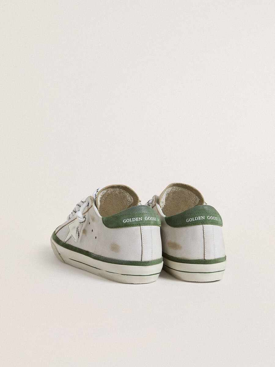 tênis feminino super-star ltd com estrela de couro branco e detalhe de camurça verde no calcanhar.