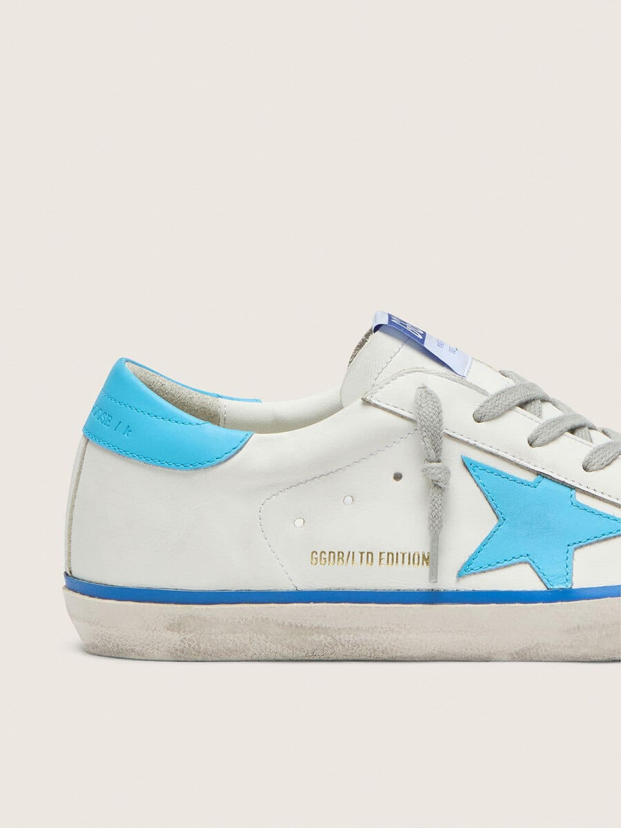 tênis super-star ltd feminino em couro branco com estrela em couro azul claro e detalhe no calcanhar.