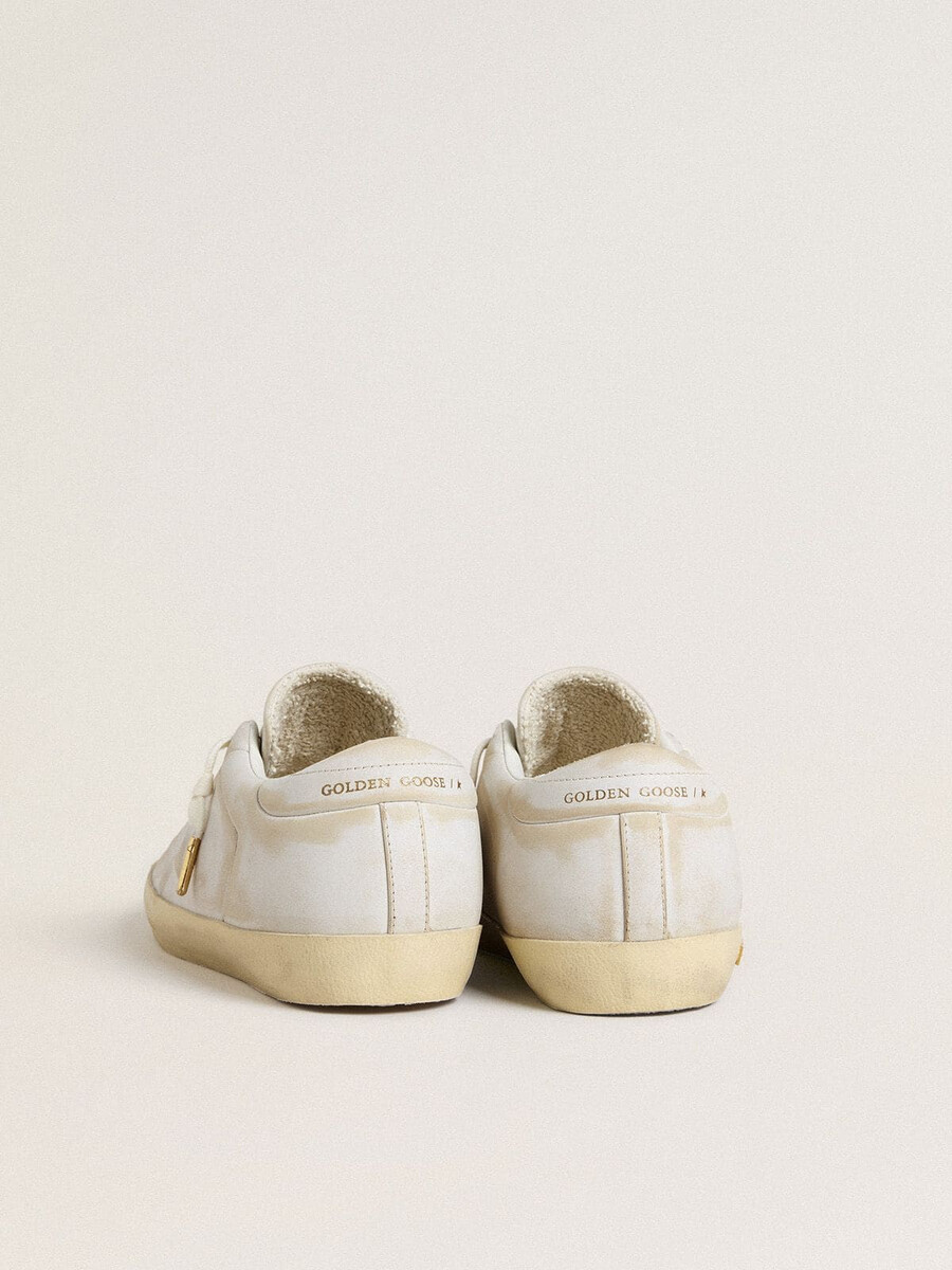 tênis feminino super-star com estrela de couro branco e detalhe no calcanhar com efeito desgastado.
