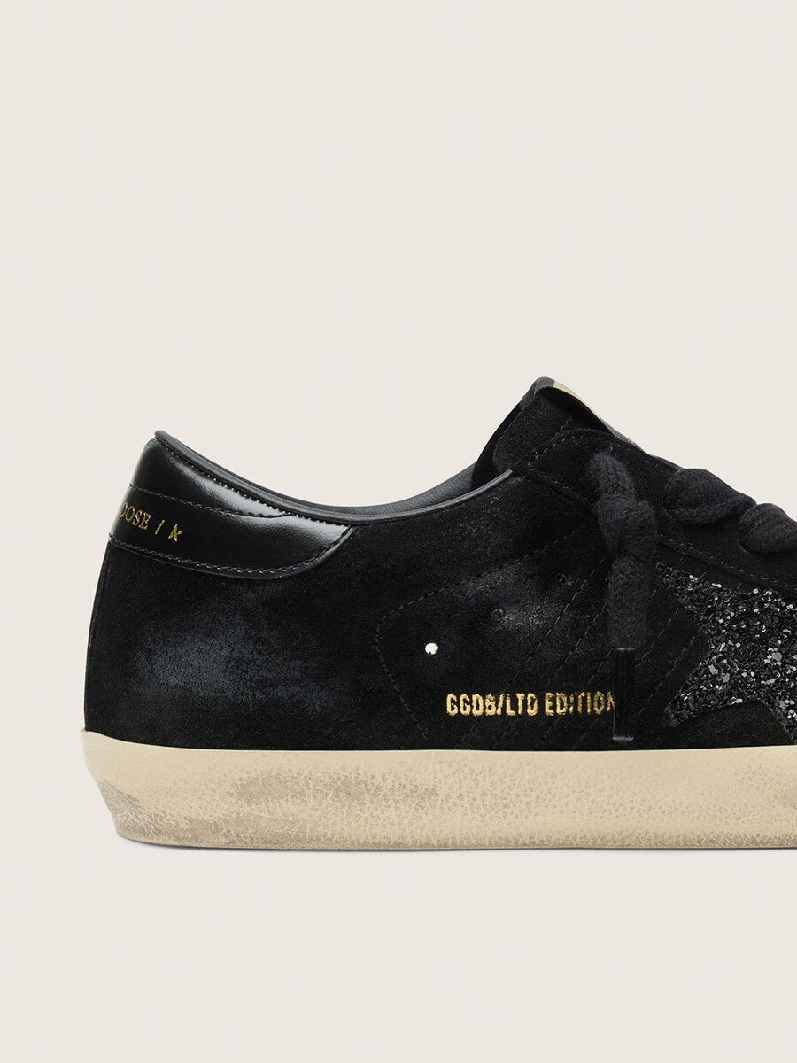 tênis super-star ltd feminino em camurça preta com estrela preta brilhante e detalhe em couro preto no calcanhar.