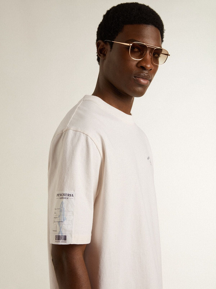 camiseta branca unissex com estampa mediterrânea e patch dourado da pescheria na manga.