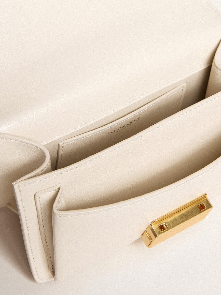 bolsa pequena venezia em couro texturizado cor manteiga com detalhes dourados.